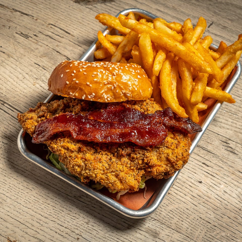 Brooklyn Wing Company's crispy chicken sandwich with bacon and fries on a metal tray.